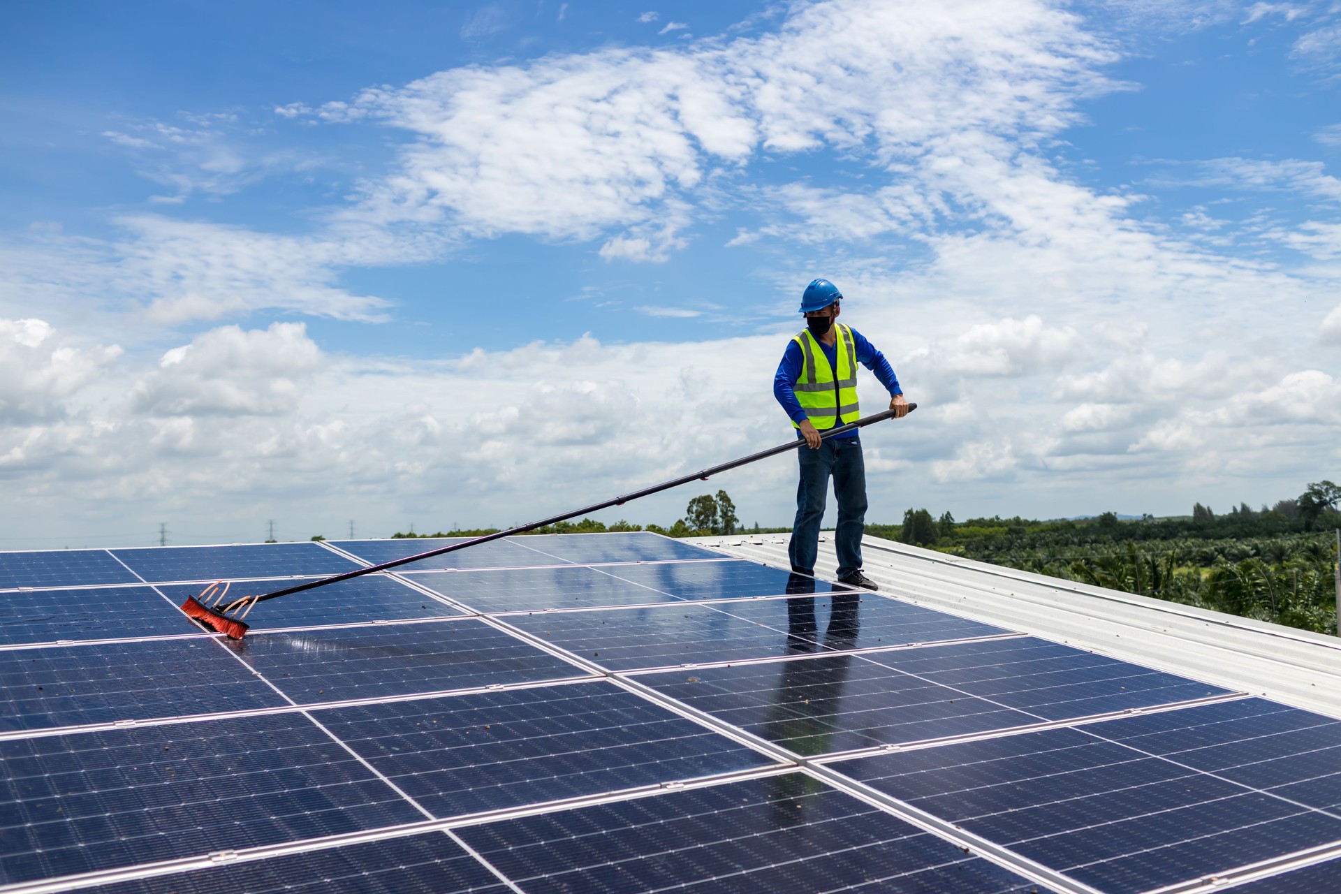 Arbeiter Reinigung von Sonnenkollektoren mit Bürste und Wasser. Arbeiter, der Solarmodule in einem Solarenergie-Stromplan reinigt